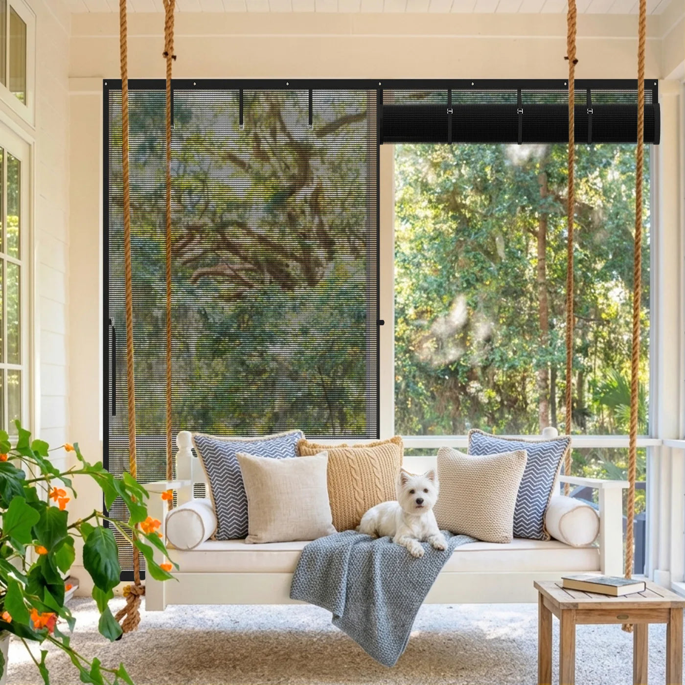 A small white dog lying on a porch swing bed in front of a roll-up magnetic screen enclosure.